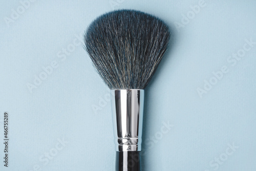 Large makeup brush on a blue background.