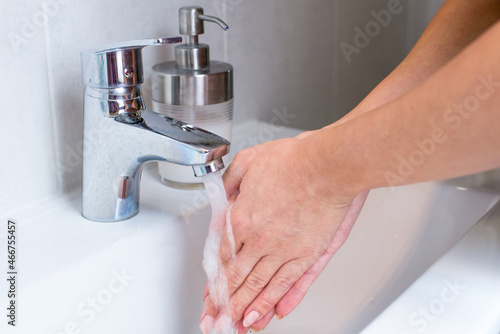 Woman use soap and washing hands rubbing with soap under the water tap. Hygiene new normal concept to stop spreading coronavirus or influenza virus.Woman use soap and washing hands under the water tap