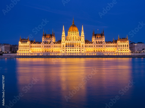 Parliament building in Budapest, Hungary. Parliament and reflections in the Danube River. Blue hour and evening illumination of the building. High resolution photo.