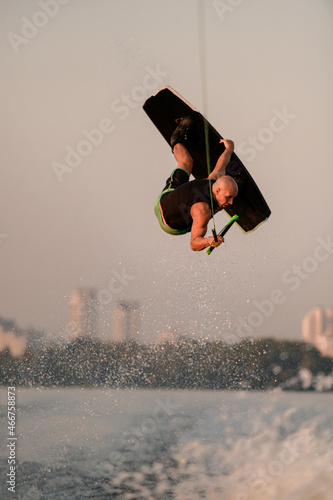 strong energy man jumping and flips on wakeboard over splashing wave photo