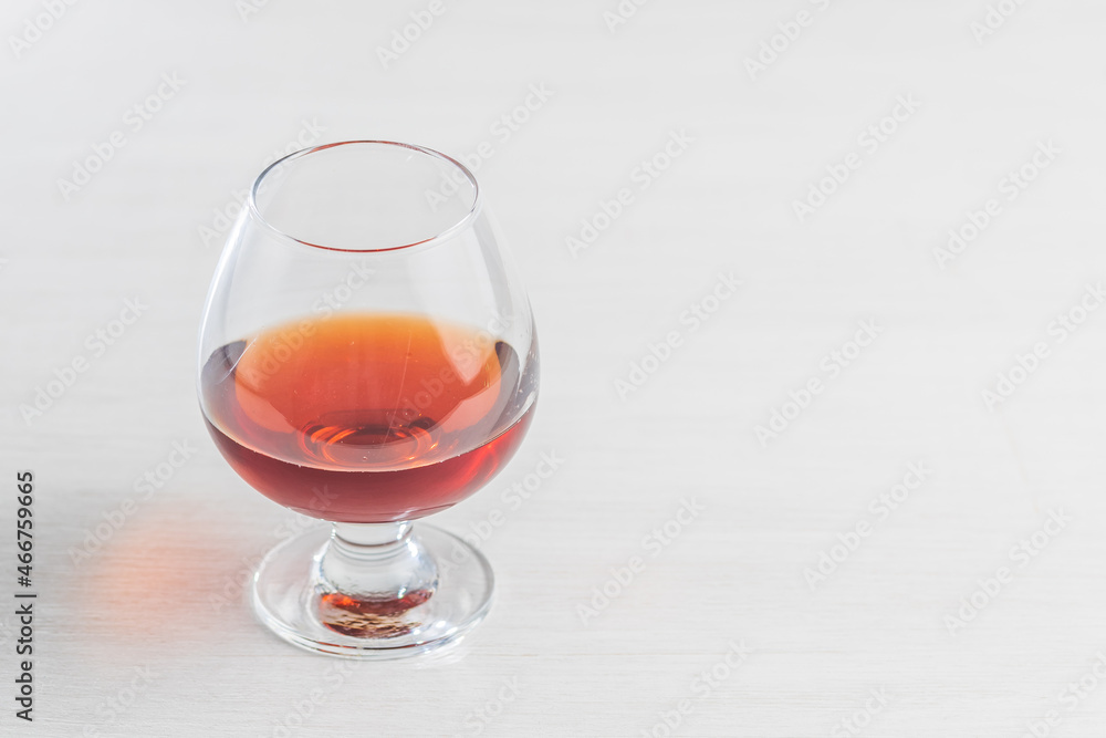 A glass of cognac or brandy on a light background. Empty space for the copy space on the right A glass of cognac or brandy on a light background. Empty space for the copy space on the right