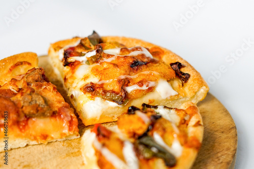 a close up look of the three slices of pizza on the wooden paddle or peel. a tasty Italian baked food with spicy topping on it.