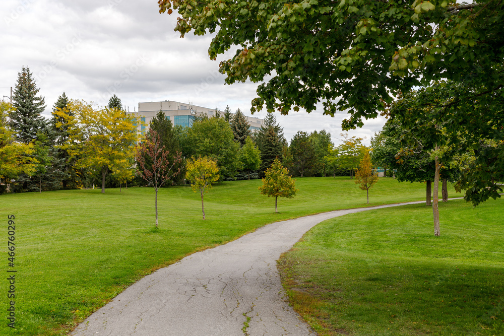 Fototapeta premium Centrepointe public park in Ottawa, Canada with trail, trees and green grass in early fall