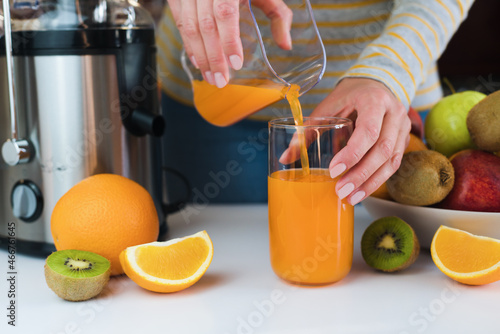 Female hands pour freshly squeezed fruit juice into a glass. Natural and healthy juices. Close-up.