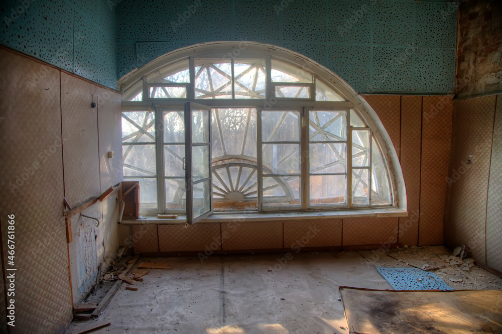Obraz premium Antique semicircular windows in an old abandoned manor house. Beautiful interior of an old abandoned building. Shabby walls. Landscape outside the window.