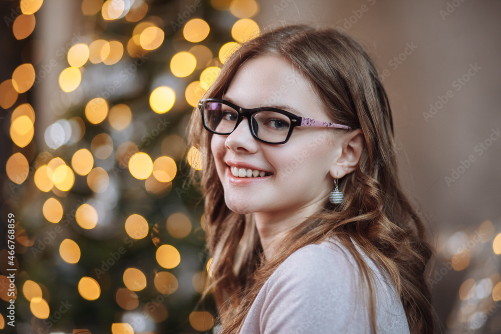 Portrait of a smiling girl on the background of a New Year tree at Christmas Portrait of a smiling girl on the background of a New Year tree at Christmas