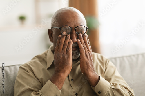 Senior African Man Rubbing Eyes Wearing Eyeglasses Having Glaucoma Indoors