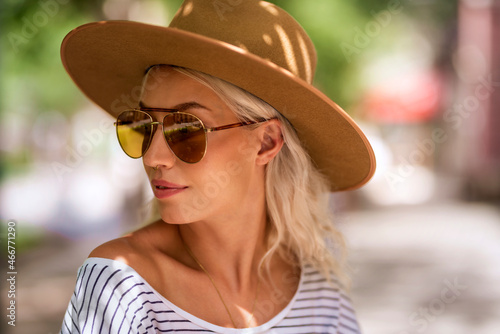 Attractive woman wearing hat and sunglasses while on outdoor