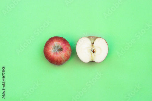 one whole apple and one half cut apple on green bakcground