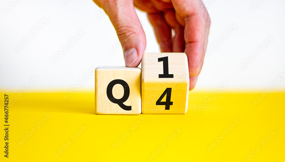 From 4th to 1st quarter symbol. Businessman turns a wooden cube and changes words 'Q4' to 'Q1'. Beautiful yellow table, white background. Business, happy 1st quarter Q1 concept, copy space. - obrazy, fototapety, plakaty 