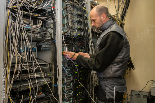 Service and maintenance of a rack with powerful network servers in the data center. The technician connects the fiber backbones to the network interfaces.