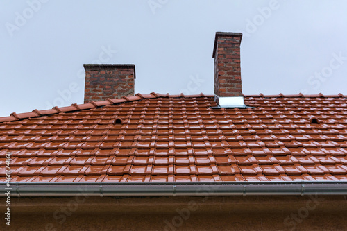 Wet red tile roof on a rainy autumn day. Light rain falls on the roof of a house