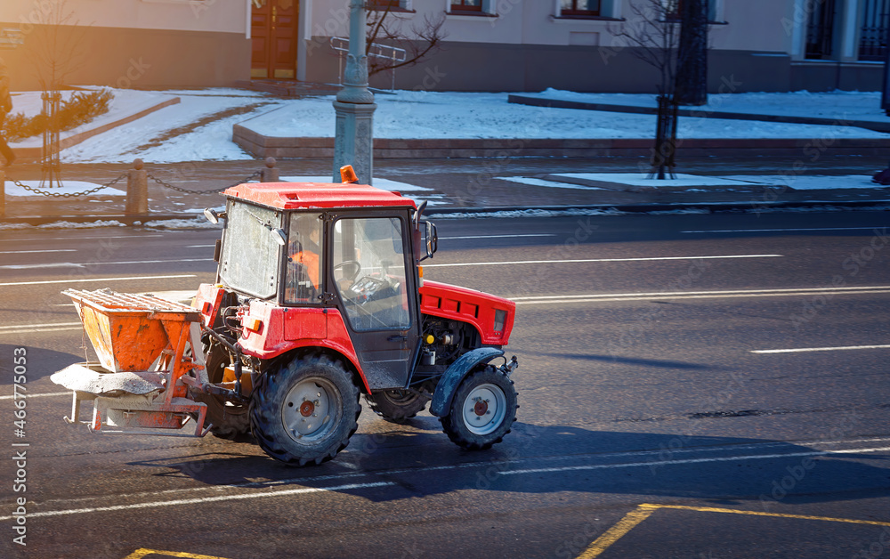 Tractor mounted self loading salt spreader riding on city road, tractor