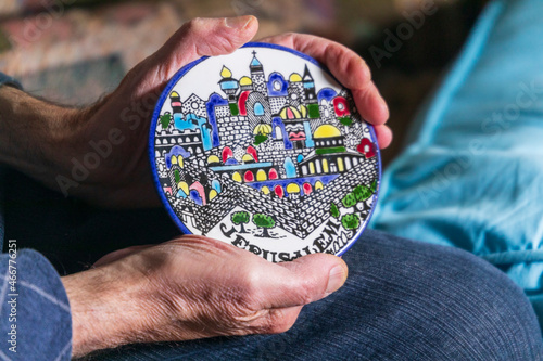 A man holds a souvenir plate with a picture of Israel and Jerusalem