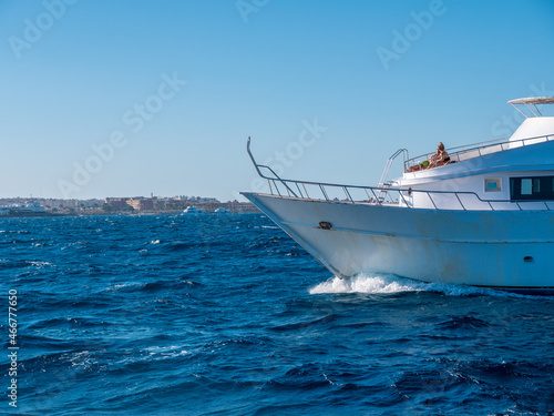 A boat with tourists sails along the coast with hotels.