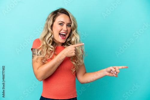 Young Brazilian woman isolated on blue background surprised and pointing side