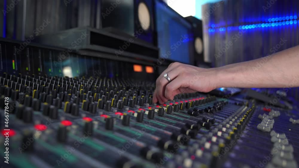 Professional mixing console in the studio, female hand controls the