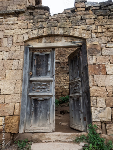 Old wooden door opened in the ruined house of the village of the ghost of Gamsutl