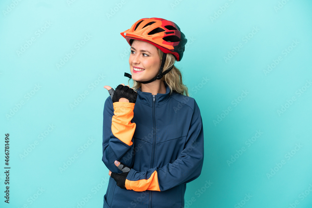 Young cyclist woman isolated on blue background pointing to the side to present a product Young cyclist woman isolated on blue background pointing to the side to present a product