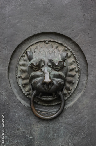 rusty metal antique lion's head doorknocker on gray stone