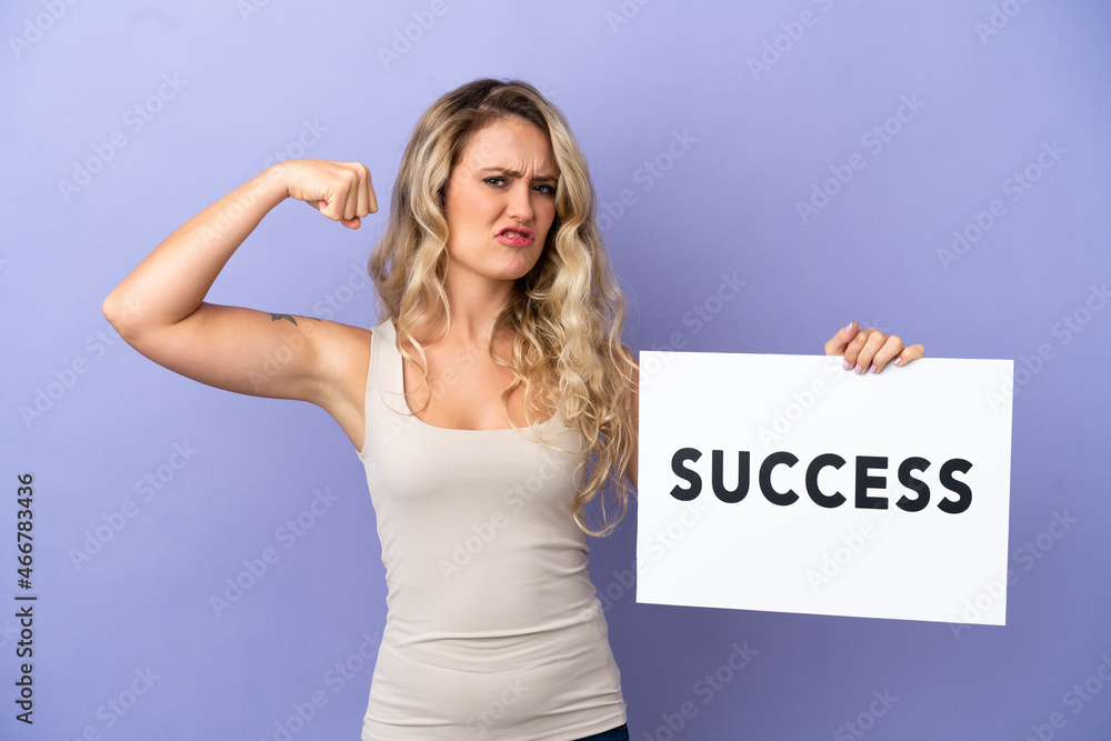 Young Brazilian woman isolated on purple background holding a placard with text SUCCESS and doing strong gesture Young Brazilian woman isolated on purple background holding a placard with text SUCCESS and doing strong gesture