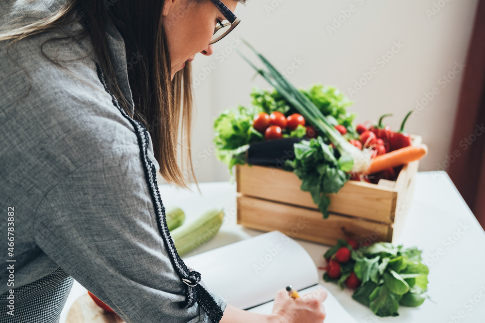 Beautiful Woman Looking for Healthy Recipes in her Cookbook at Kitchen Desk