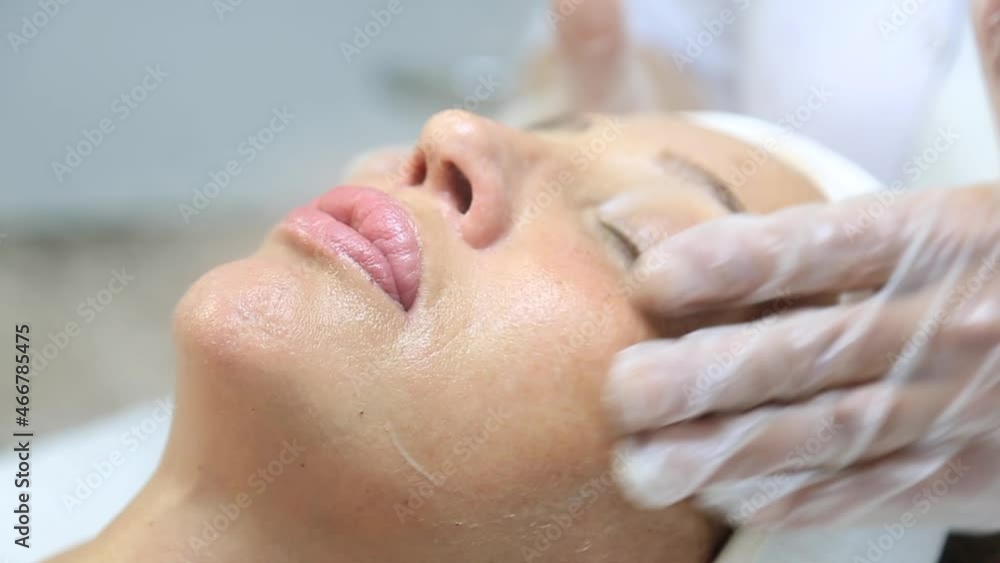 Facial peeling mask, spa beauty treatment, skin care. Woman getting facial treatment by beauty at spa salon, side view close up. Beautiful woman getting face massage in beauty spa Facial peeling mask, spa beauty treatment, skin care. Woman getting facial treatment by beauty at spa salon, side view close up. Beautiful woman getting face massage in beauty spa