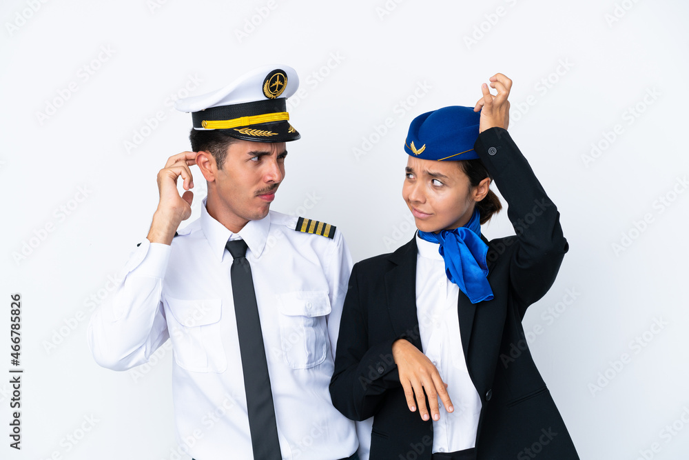 Airplane pilot and mixed race air hostess isolated on white background having doubts while scratching head Airplane pilot and mixed race air hostess isolated on white background having doubts while scratching head