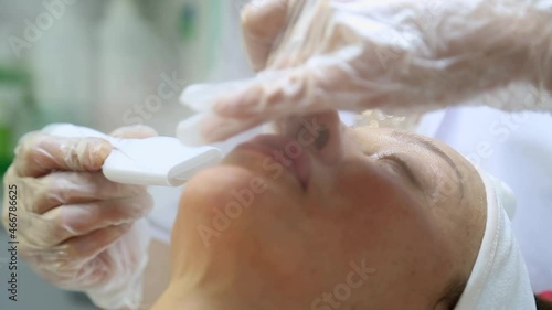 Facial peeling mask, spa beauty treatment, skin care. Woman getting facial treatment by beauty at spa salon, side view close up. Beautiful woman getting face massage in beauty spa