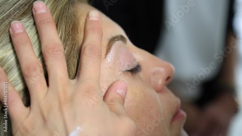 Process of making makeup. Make-up artist working with brush on model face. Portrait of young brunette woman in beauty saloon interior. Applying tone to skin.