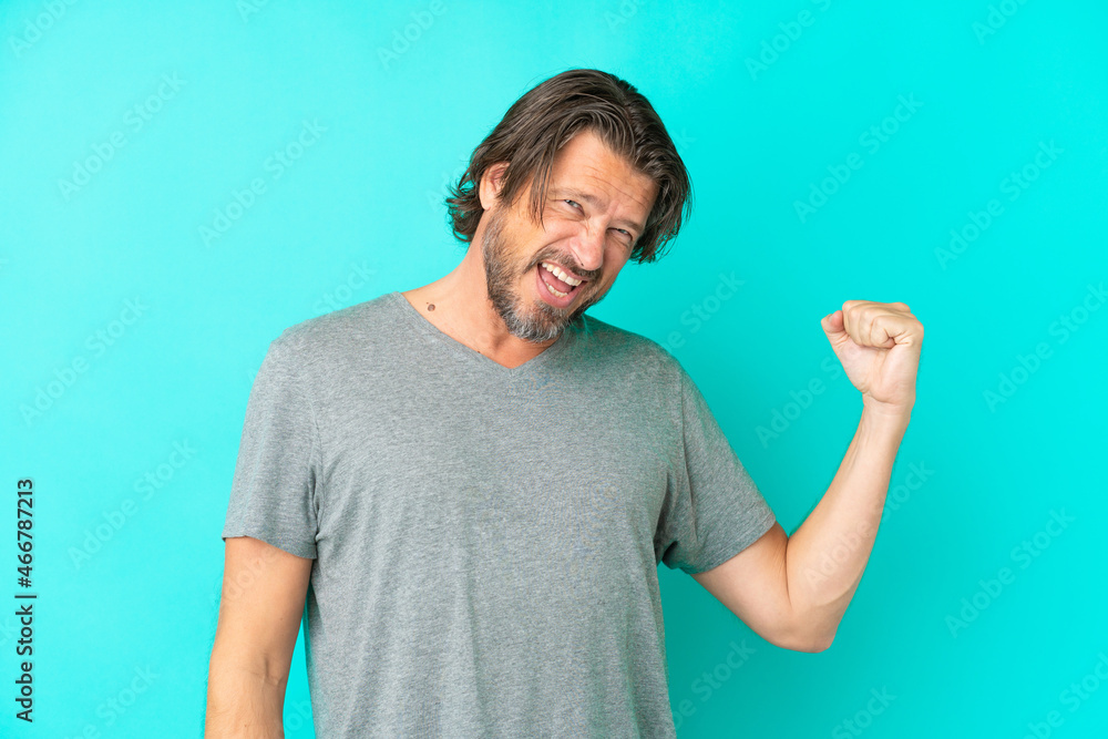 Senior dutch man isolated on blue background celebrating a victory Senior dutch man isolated on blue background celebrating a victory