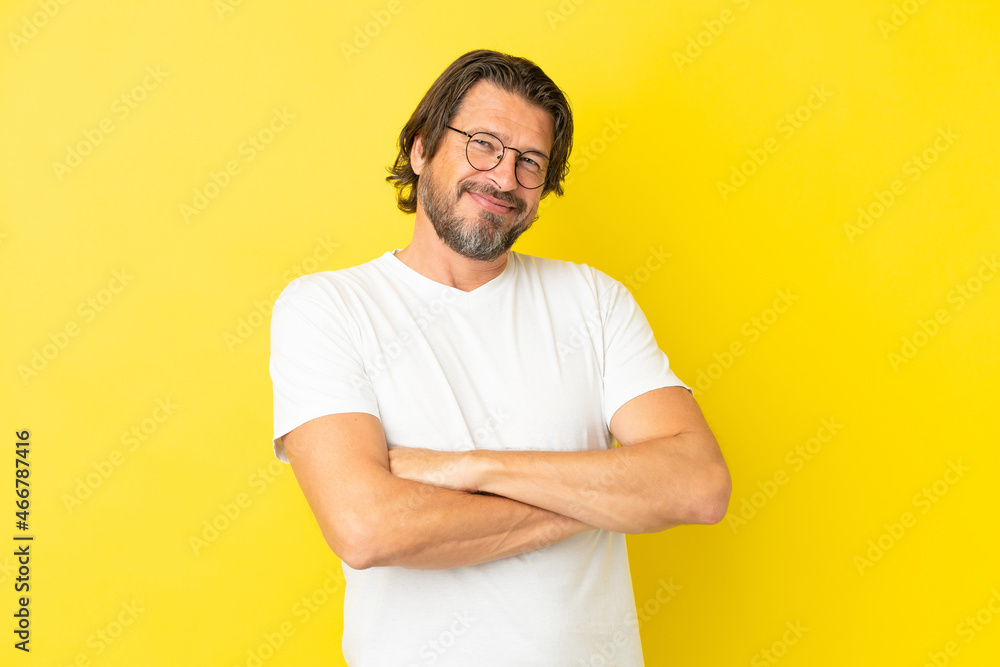 Senior dutch man isolated on yellow background keeping the arms crossed in frontal position Senior dutch man isolated on yellow background keeping the arms crossed in frontal position