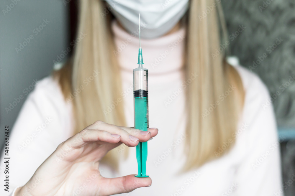 Young female doctor with mask hold syringe isolated on light background Young female doctor with mask hold syringe isolated on light background