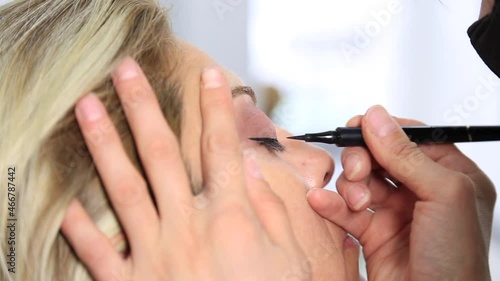 Process of making makeup. Make-up artist working with brush on model face. Portrait of young brunette woman in beauty saloon interior. Applying tone to skin.