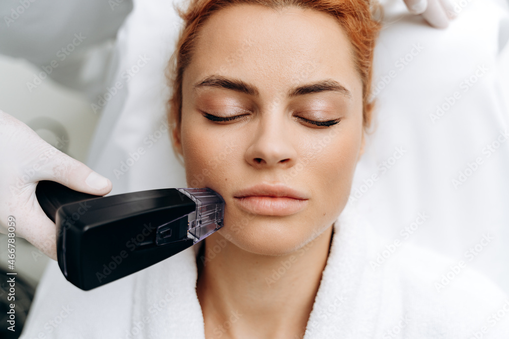 Effective hair removal procedure. Close up of beautician in sterile gloves  placing laser epilation machine on lady face and gliding device over the  skin Photos | Adobe Stock