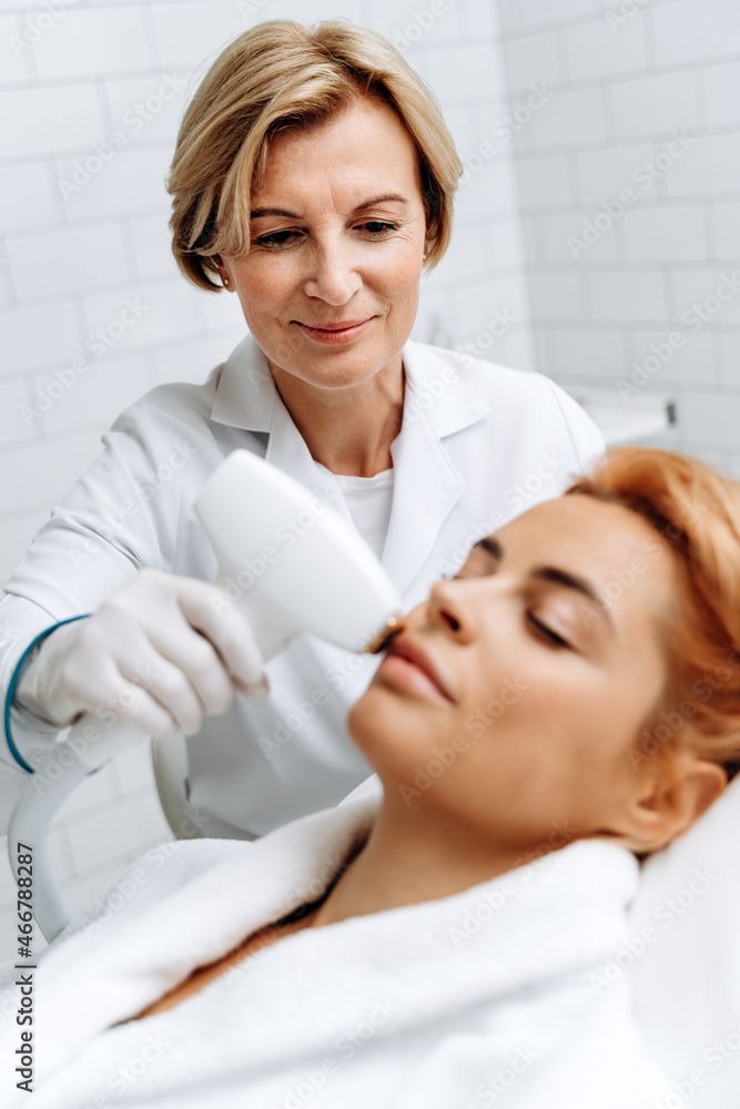 Aesthetic face treatment. Close up face portrait of young careful woman having laser hair removal procedure of chin zone by specialist in cosmetic center Aesthetic face treatment. Close up face portrait of young careful woman having laser hair removal procedure of chin zone by specialist in cosmetic center