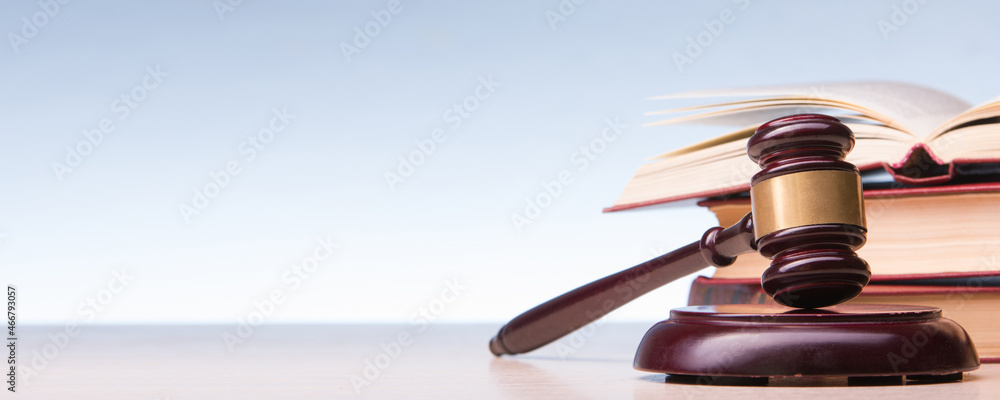 Law concept - Open law book with a wooden judges gavel on table in a courtroom or law enforcement office isolated on white background. Copy space for text. - obrazy, fototapety, plakaty 