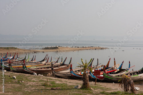 Colourful painted fishermen boats resting at the lake shore in the early morning sun at Taungthaman In Lake (Myanmar) nearby U-Bein Bridge.