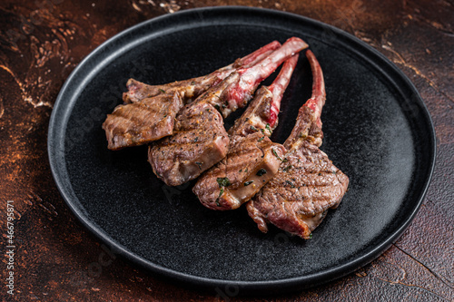 BBQ Grilled lamb chops steaks in a plate. Dark background. Top view