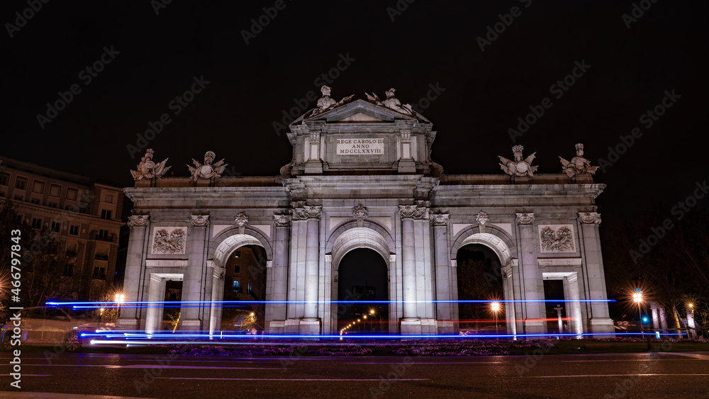Puerta de Alcalá with blue lights of a police car, in the city of madrid during a clear night