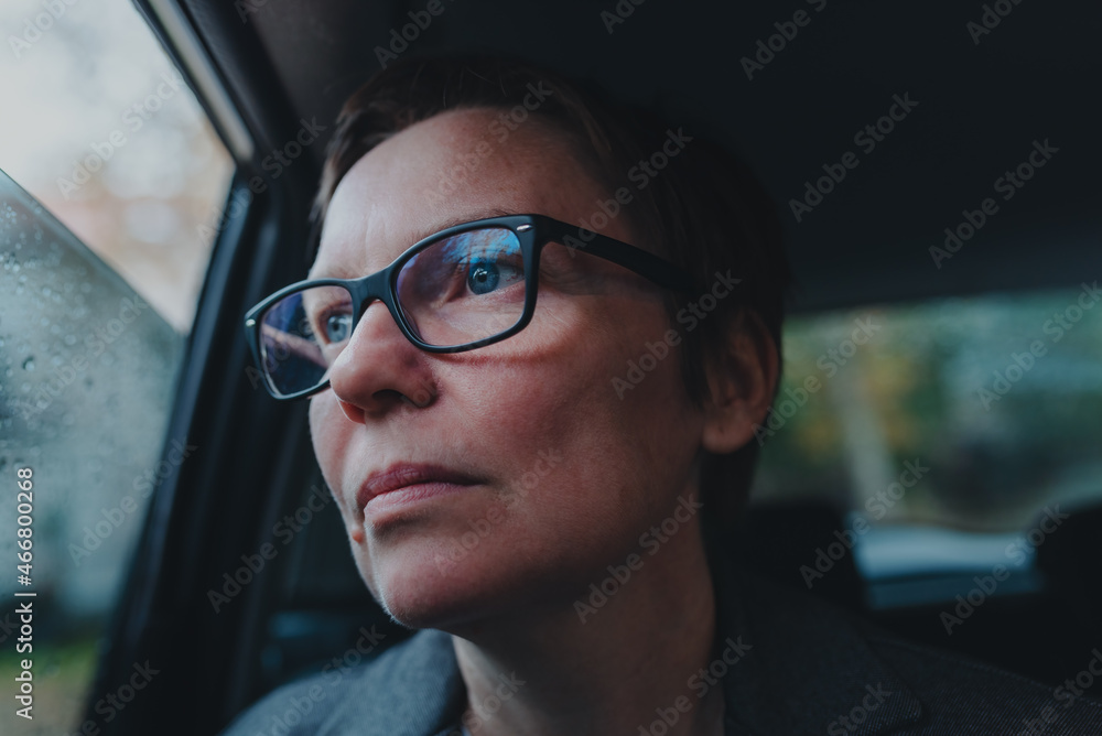 Worried businesswoman with eyeglasses waiting in the car and looking out the window during rain Worried businesswoman with eyeglasses waiting in the car and looking out the window during rain