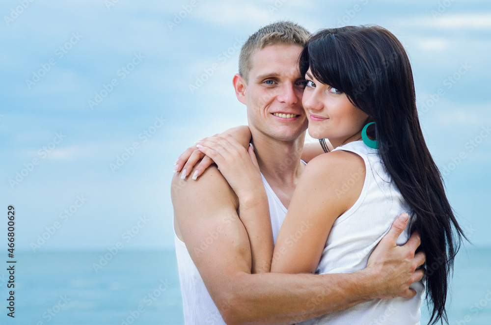 guy and a girl in jeans and white t-shirts on the beach