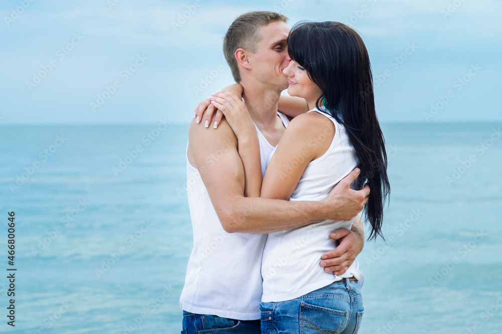 guy and a girl in jeans and white t-shirts on the beach guy and a girl in jeans and white t-shirts on the beach
