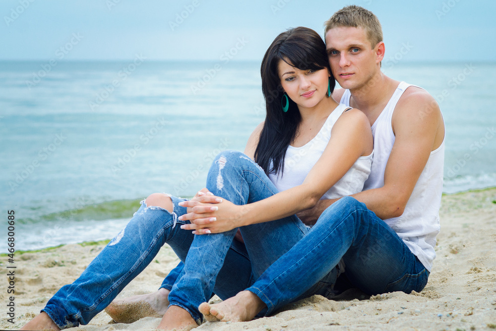 guy and a girl in jeans and white t-shirts on the beach