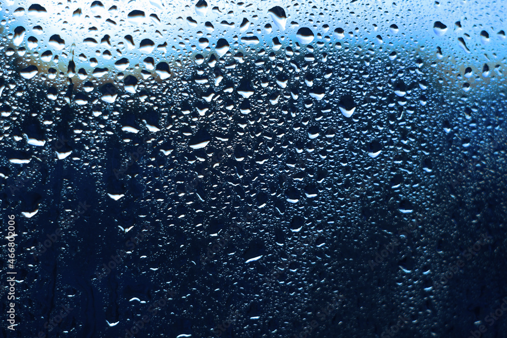 Water rain drops on window glass, closeup view.Blue color background Water rain drops on window glass, closeup view.Blue color background