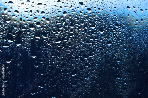 Water rain drops on window glass, closeup view.Blue color background