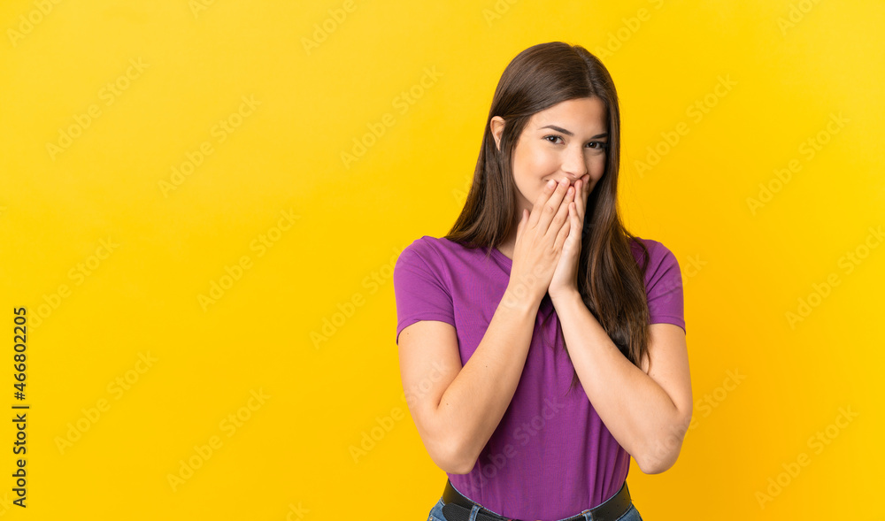 Teenager Brazilian girl over isolated yellow background happy and smiling covering mouth with hands Teenager Brazilian girl over isolated yellow background happy and smiling covering mouth with hands