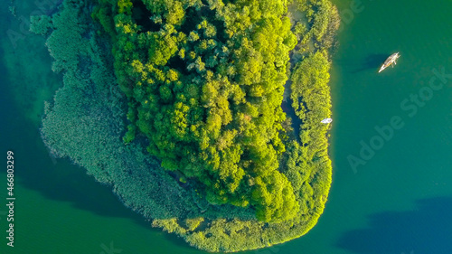 Bird's eye view of the green island in the middle of the lake in a daylight.