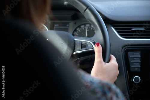 Detail of a woman's hand holding a steering wheel and driving a car