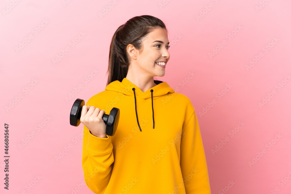 Young sport girl making weightlifting over isolated pink background looking side Young sport girl making weightlifting over isolated pink background looking side